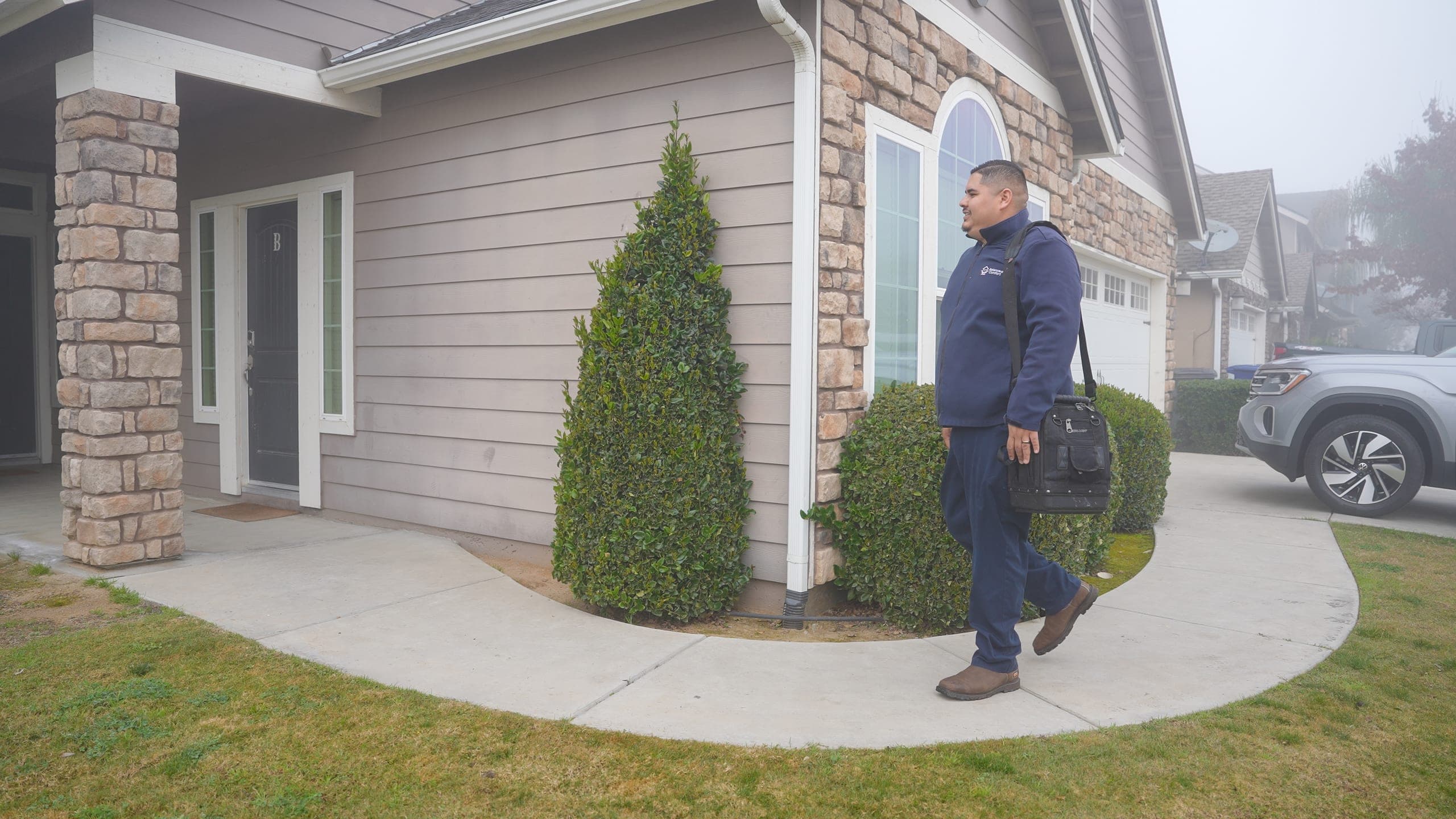 A Balanced Comfort technician in uniform approaching a home to begin a service call