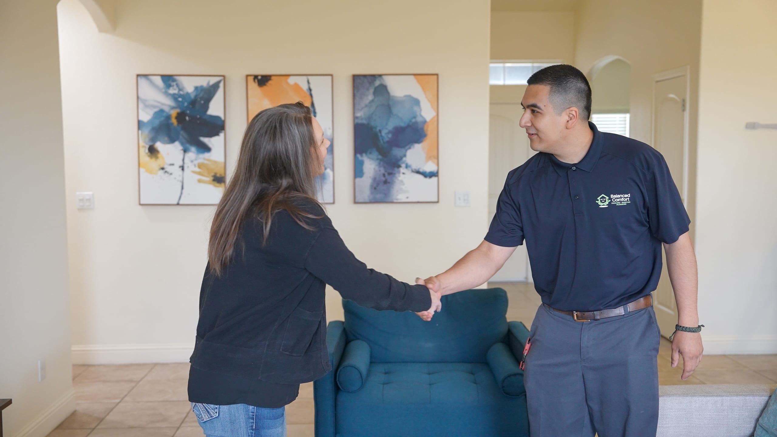 A Balanced Comfort technician smiling and shaking hands with a homeowner