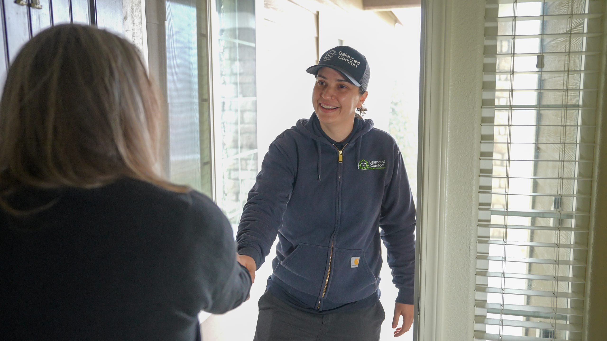 A Balanced Comfort technician greeting a happy customer at the door