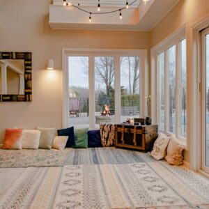 house with white carpet and assortment of pillows. Firepit outside in background