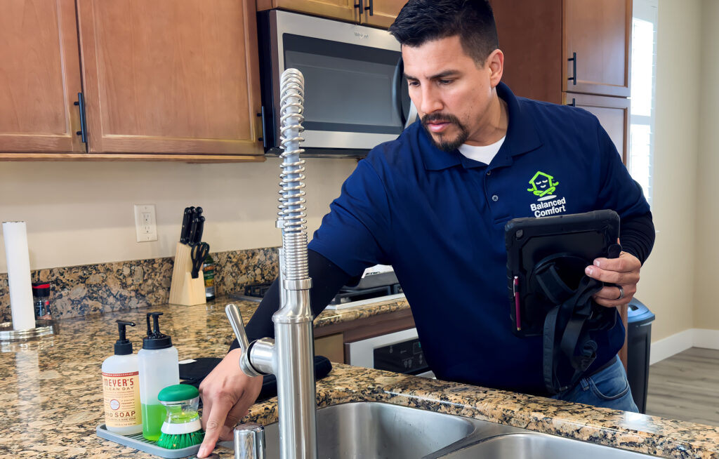 A plumber checking a kitchen faucet for leaks and proper performance